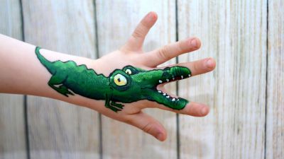 Kinderschminken - Krokodilzeichnung auf dem Arm mit Fingern als Maul